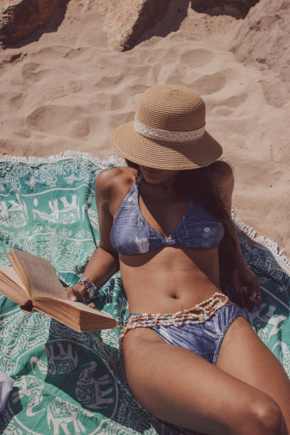 istock Young female lying on the sandy beach and reading a book 1460191291
