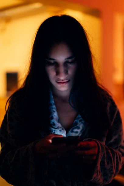 istock Young woman in dressing gown using a phone at night at home 1460191759