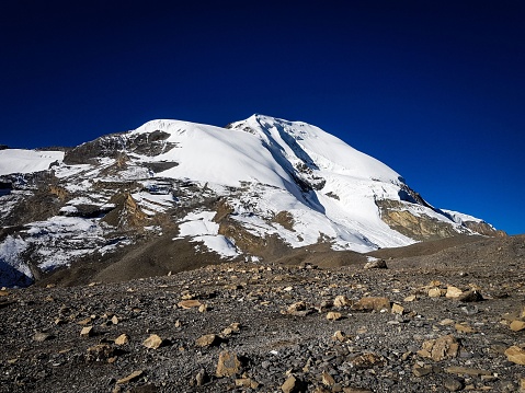 A snow-covered mountain captured from the mountain pass Thorong la pass against the blue cloudless sky