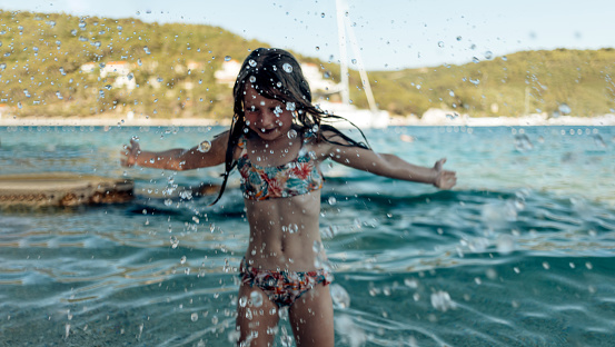 Happy young girl having fun playing on the beach - Soft focus on water drops