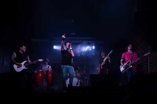 A young energetic rock band performing during a concert in a club