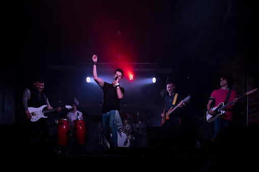 A young energetic rock band performing during a concert in a club