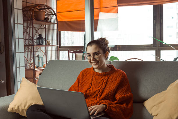 istock Caucasian woman working through her laptop while seated on the couch - work from home concept 1460195214