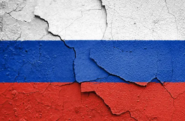 Flag of Russia painted on a cracked wall. Embargo and sanctions for military aggression.