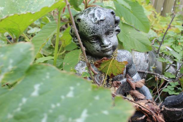 a small stone statue of a boy among green leaves