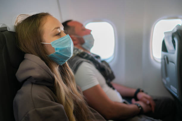 istock Young woman wearing face mask on board on airplane 1460195951