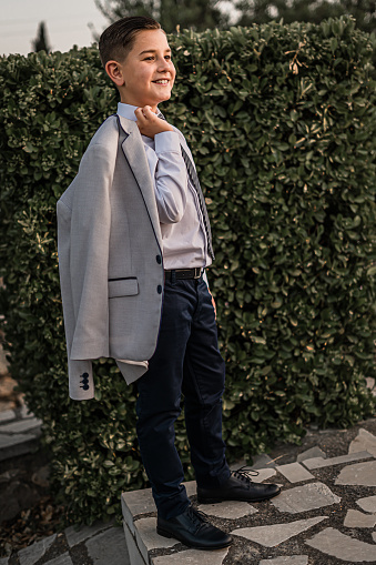 A vertical shot of an adorable male child in a formal suit outfit