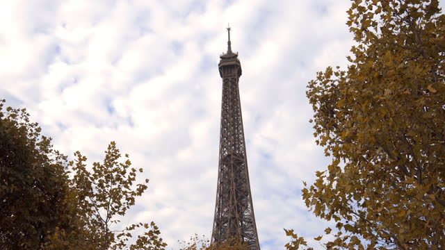 Top of the Eiffel Tower seen on a Fall day with white clouds in Paris