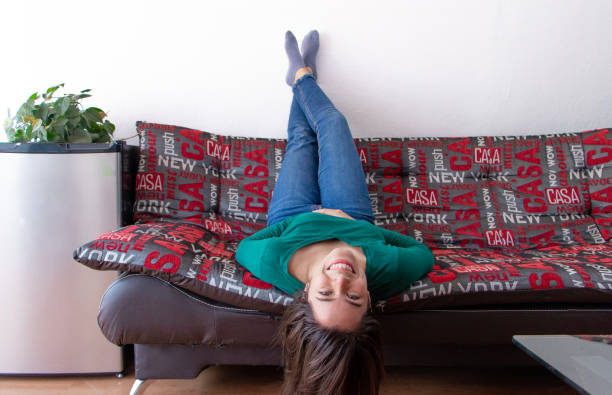 istock Young cheerful Hispanic lady lying on the couch upside down 1460198476