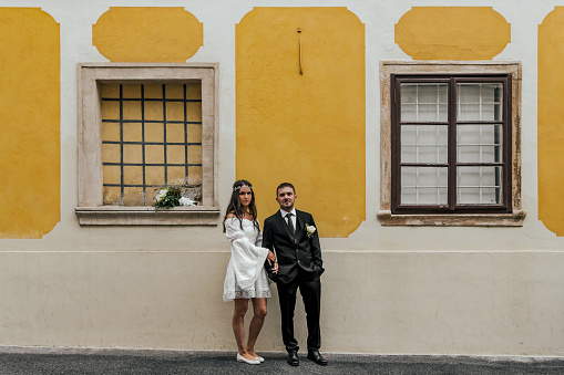 Beautiful bride and groom standing in front of yellow building at Gornji Grad in Zagreb, Croatia.