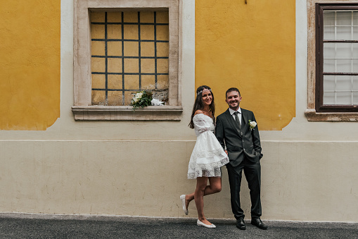 Beautiful bride and groom standing in front of yellow building at Gornji Grad in Zagreb, Croatia.