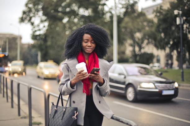 istock Young stylish black female walking outdoors with a takeaway coffee 1460199822