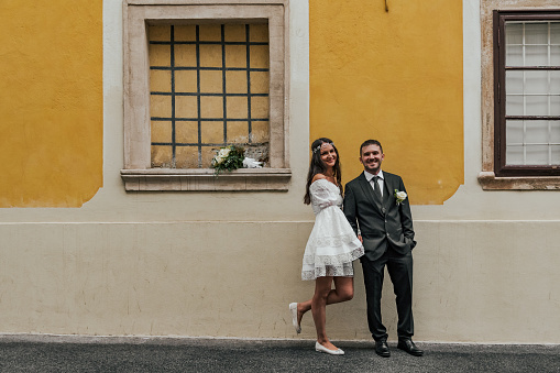 Beautiful bride and groom standing in front of yellow building at Gornji Grad in Zagreb, Croatia.