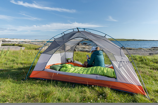 A female traveler sitting in the tent on Dog's Bay beach in Galway Ireland