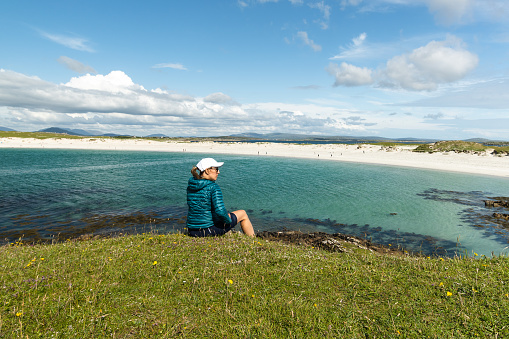 A female traveler admiring the scenery on Dog's Bay beach in Galway Ireland