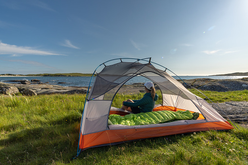 A female traveler sitting in the tent on Dog's Bay beach in Galway Ireland