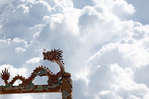 A dragon sculpture on the roof, with a beautiful view of fluffy clouds in the background