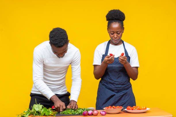 istock Young African couple learning to cook together on a yellow background 1460201437