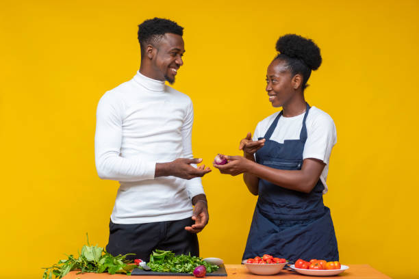 istock Young African couple learning to cook together on a yellow background 1460201523