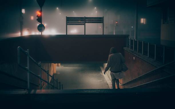 Person walking down a stairs to a subway at night
