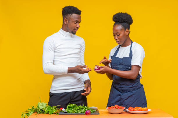 istock Young African couple learning to cook together on a yellow background 1460201776