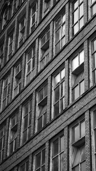 A vertical of a windows on a brick building of a factory shot in grayscale