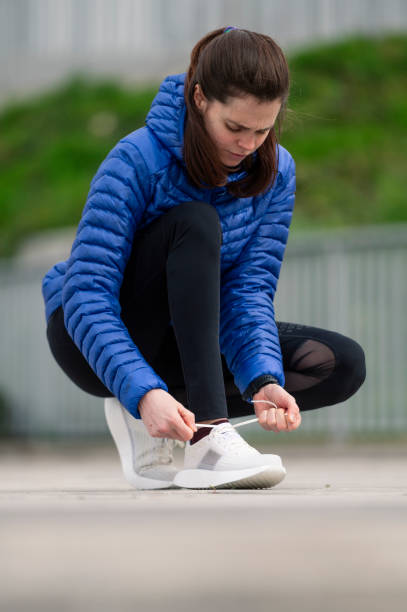 istock Female jogger tying her shoelaces in a park 1460202195