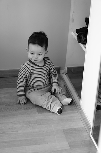 A grayscale shot of a toddler boy playing on the floor