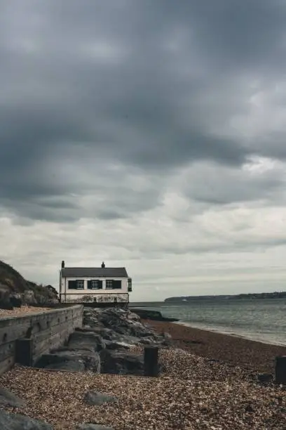 A vertical shot of an old coastguard watchhouse under a cloudy sky at Lepe Beach, Hampshire, UK.