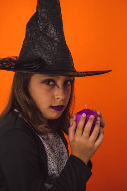 istock Little Halloween witch holding a candle on an orange background 1460204081