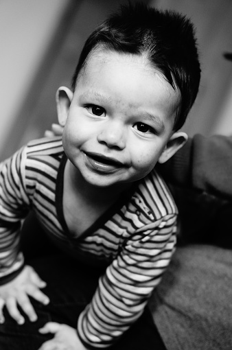 A greyscale portrait of a Caucasian little smiling boy