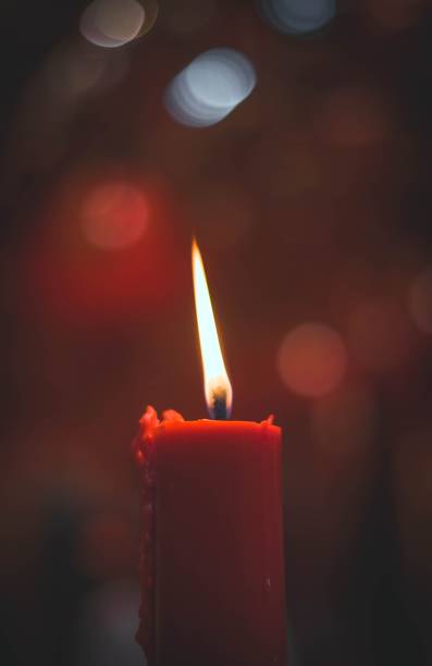 istock Vertical shot of a single burning candle in the dark on a blurry bokeh light background 1460205379