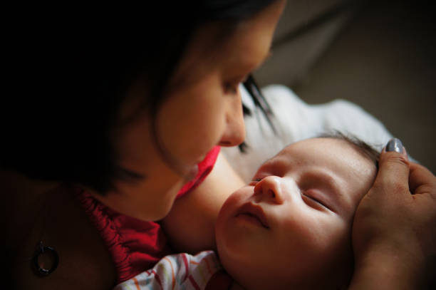 Loving happy mum carrying of newborn baby at home. Portrait parent of holding infant child on hands. Mother care little 6 months old child. Concept of motherhood and parental care. Copy space
