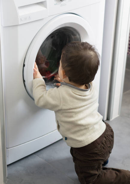 istock Little toddler looking into a washing machine 1460208112
