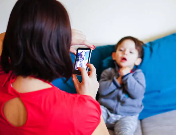 A Caucasian Woman taking a photo of a two years old boy with a Nokia Lumia Windows smartphone at home