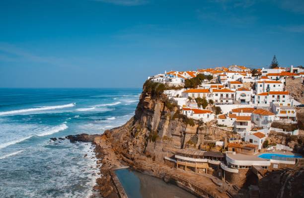 Aerial shot of white buildings with red roofs on a cliff by a sea in Azenhas do Mar, Portugal An aerial shot of white buildings with red roofs on a cliff by a sea in Azenhas do Mar, Portugal azenhas do mar stock pictures, royalty-free photos & images