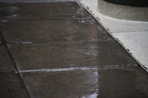 A closeup of a wet ground with grey tiles captured after rain