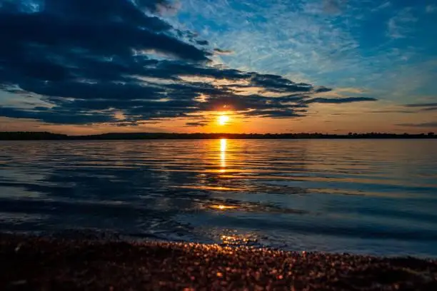 A landscape shot of Holden Lake reflecting the beautiful sunset light coming from behind the clouds