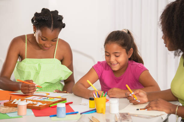 istock Latin young student drawing with her two African American teachers in school activity 1460210370