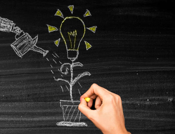istock Human hand is watering a growing bright light bulb plant 1460211150