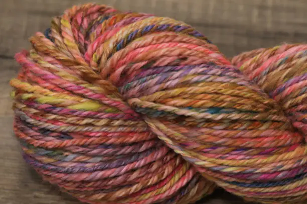 Closeup of colourful handspun and handdyed merino sheep wool, spun on a spinning wheel