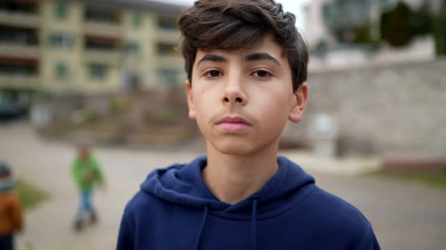 Portrait of a young teenager boy standing outside. Closeup face of male teen kid in tracking shot camera movement