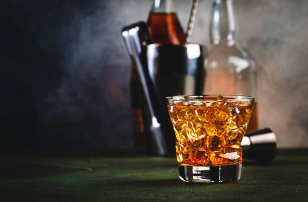 godfather cocktail with scotch whiskey, amaretto liqueur and ice. dark bar counter background, bar tools, copy space - hard liqueur imagens e fotografias de stock