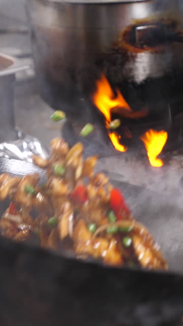 close up of a wok in slow motion, with the ingredients and fire, vertical video