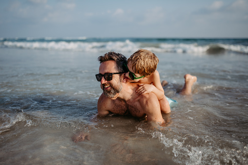 Father with his little son in sea, enjoying summer vacation.