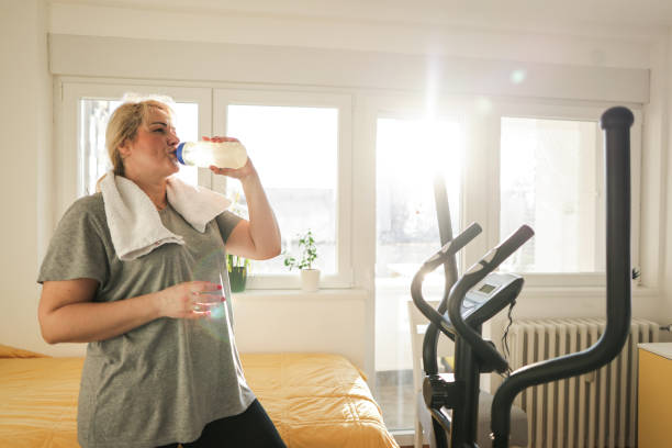 istock Woman drinking water, after she finished with exercises on an ski exercise machine 1460221550