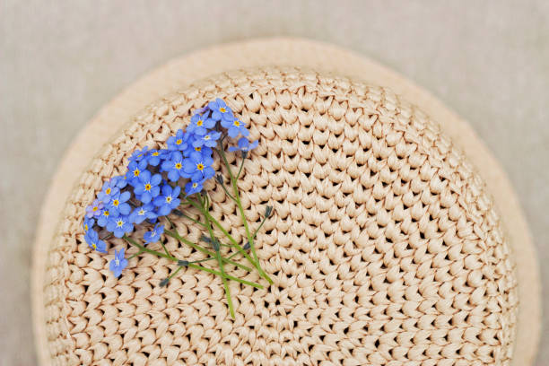 still life with natural raffia crochet hat and forget me not blue flowers bouquet