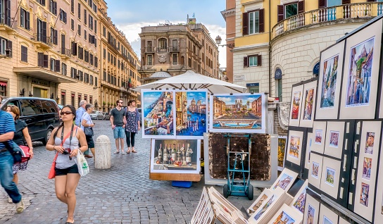 Rome, Italy - June 18, 2014. Colorful paintings for sale on a summer day on a cobblestone street in central Rome.