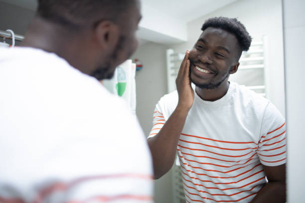 istock Smiling young man applying moisturizer to his face 1460229588