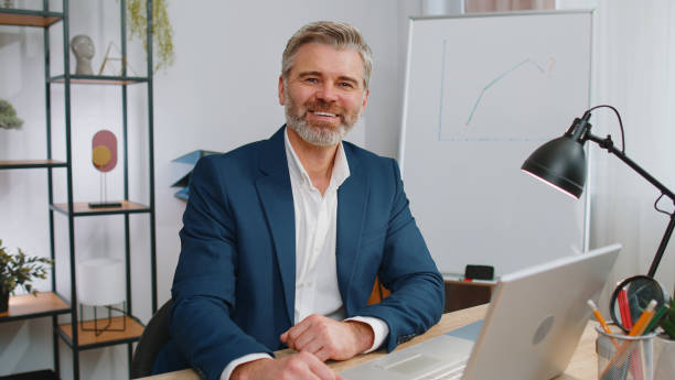 istock Mature business man freelancer at office, start working on laptop computer, sends online messages 1460234856